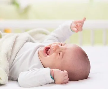 Bebé llorando tumbado en la cama