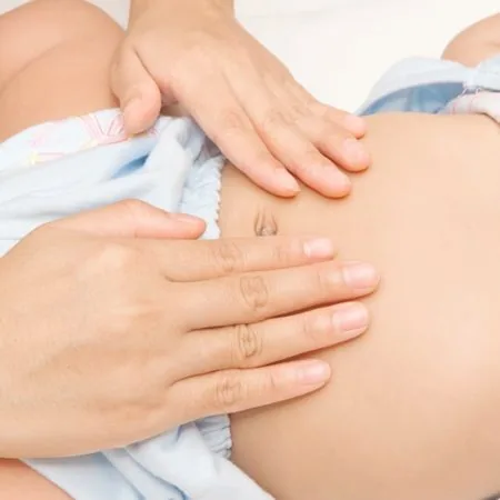 Manos de una fisioterapeuta dando un masaje abdominal a un bebé